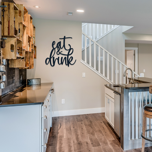 A metal sign that is hanging in the kitchen that says eat & drink.