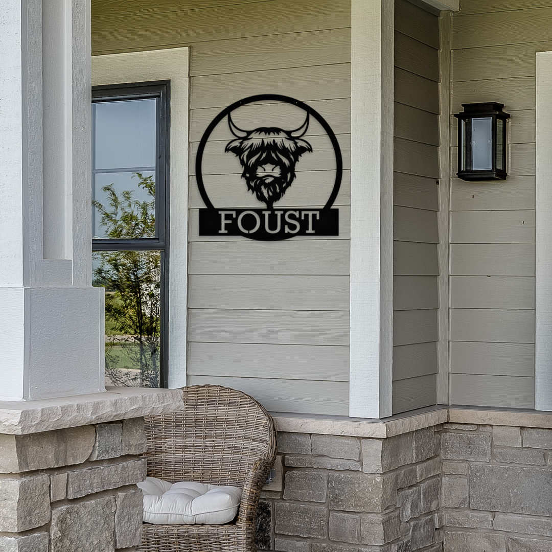 Personalized Highland Cow metal sign hanging on the front porch of a home.