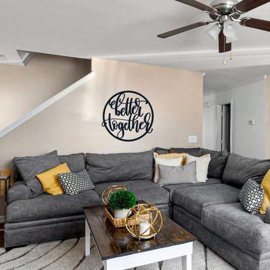 A round metal signs with the words better together in the middle. It is hanging in the living room above the couch.