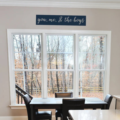 Metal sign that says you, me, and the boys that is hanging in the kitchen by the table.