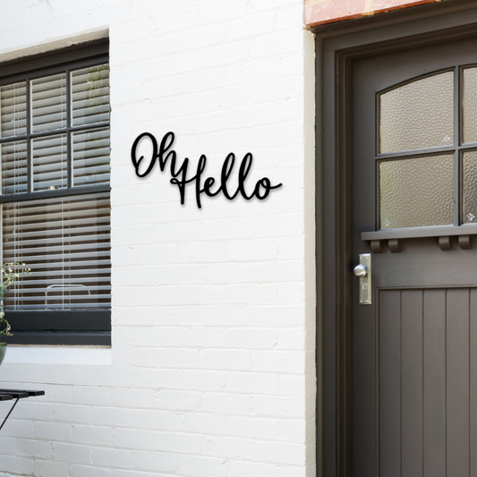 A welcome metal sign that says Oh Hello. It is hanging on the front porch by the front door.