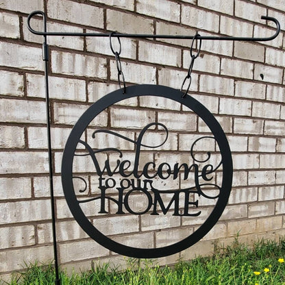 A welcome garden flag that is made out of metal and says Welcome to our home.