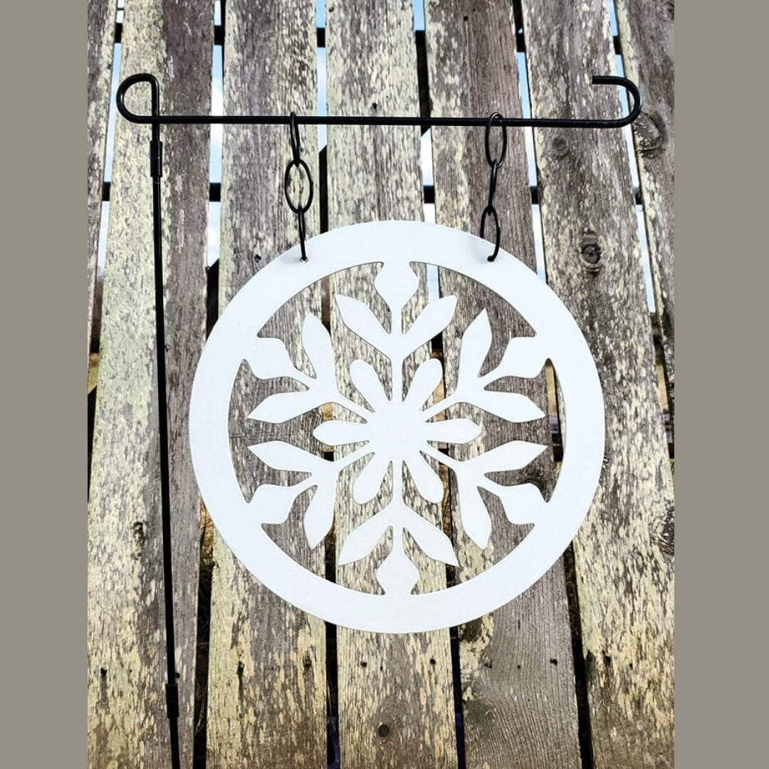 A winter garden flag that is a snowflake. It is made out of metal. 