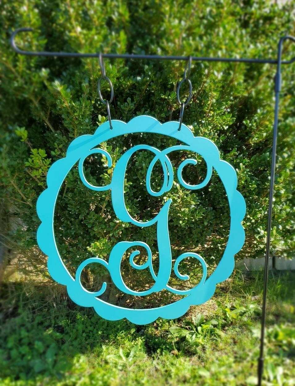 Metal yard art that is a monogram initial garden flag. 