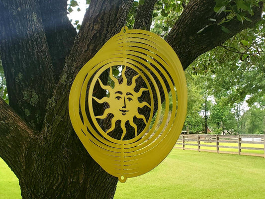 Metal Garden Art that is a Sun Wind Spinner hanging from a tree.