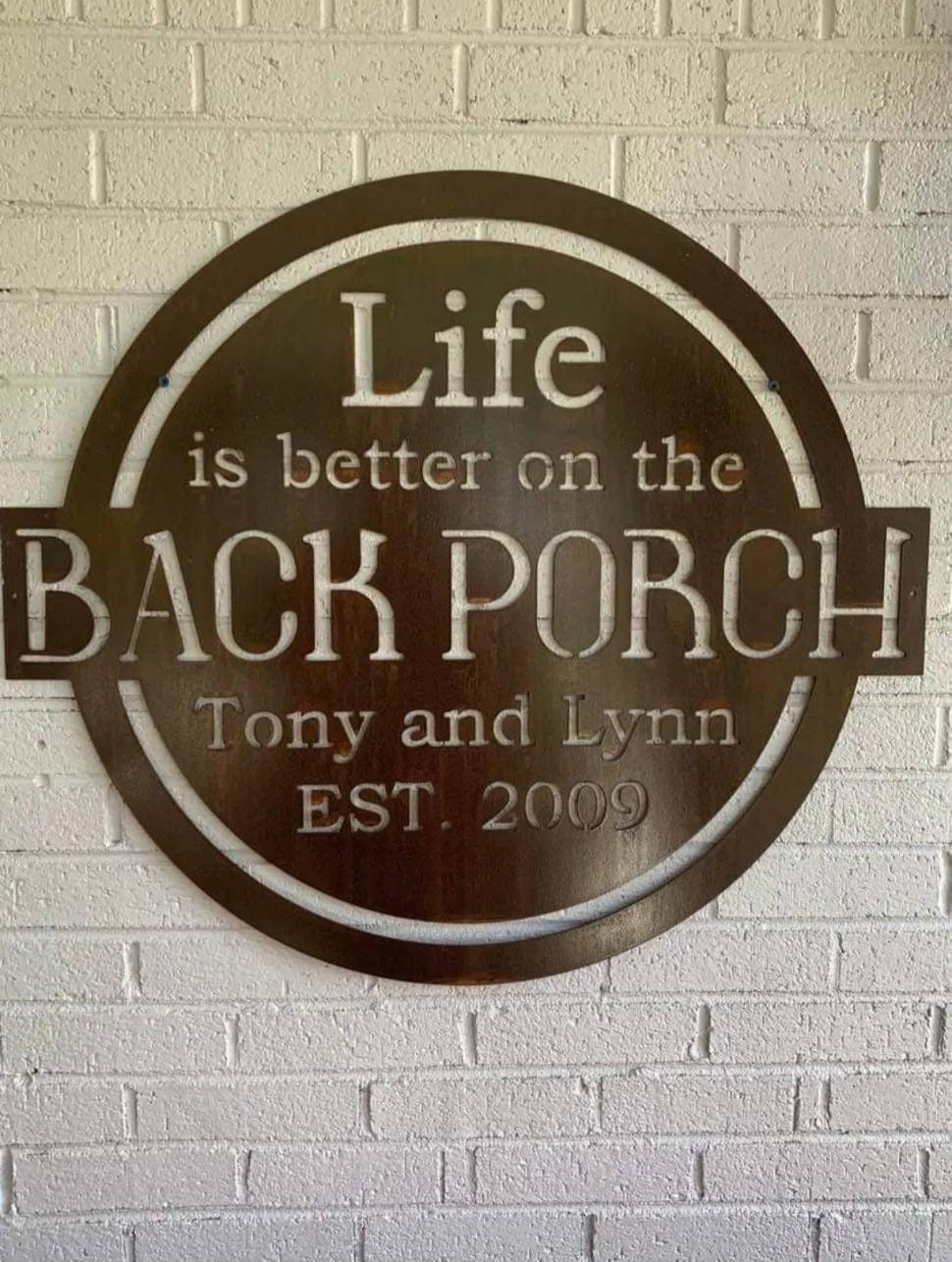 Personalized back porch metal sign that is hanging on the brick wall of the porch.