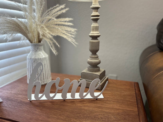 Metal Home sign that is sitting on an end table in a living room.