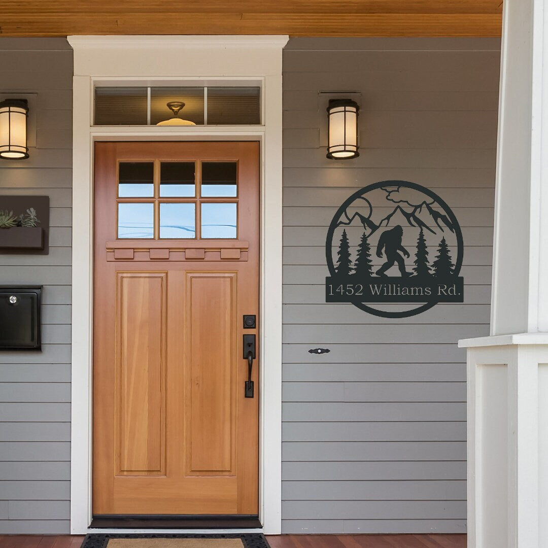 Bigfoot Metal Address Sign hanging by the front door. It has mountains and trees in the sign as well. 