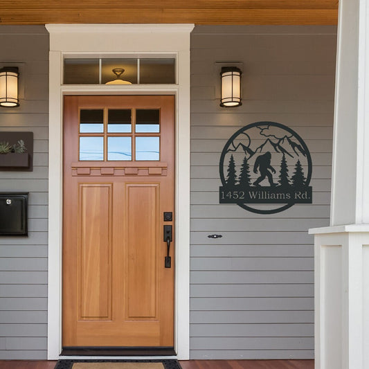 Bigfoot Metal Address Sign hanging by the front door. It has mountains and trees in the sign as well. 