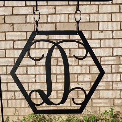 A monogram initial garden flag that is made of metal and in the shape of a hexagon.