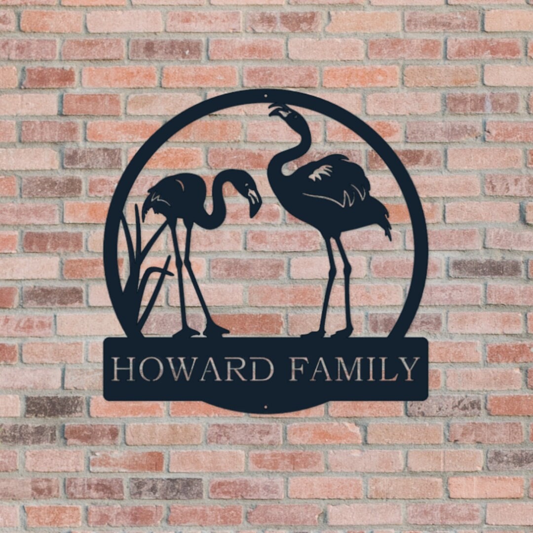 Custom metal sign that has two flamingos in the middle of the circle. This is on a brick background.