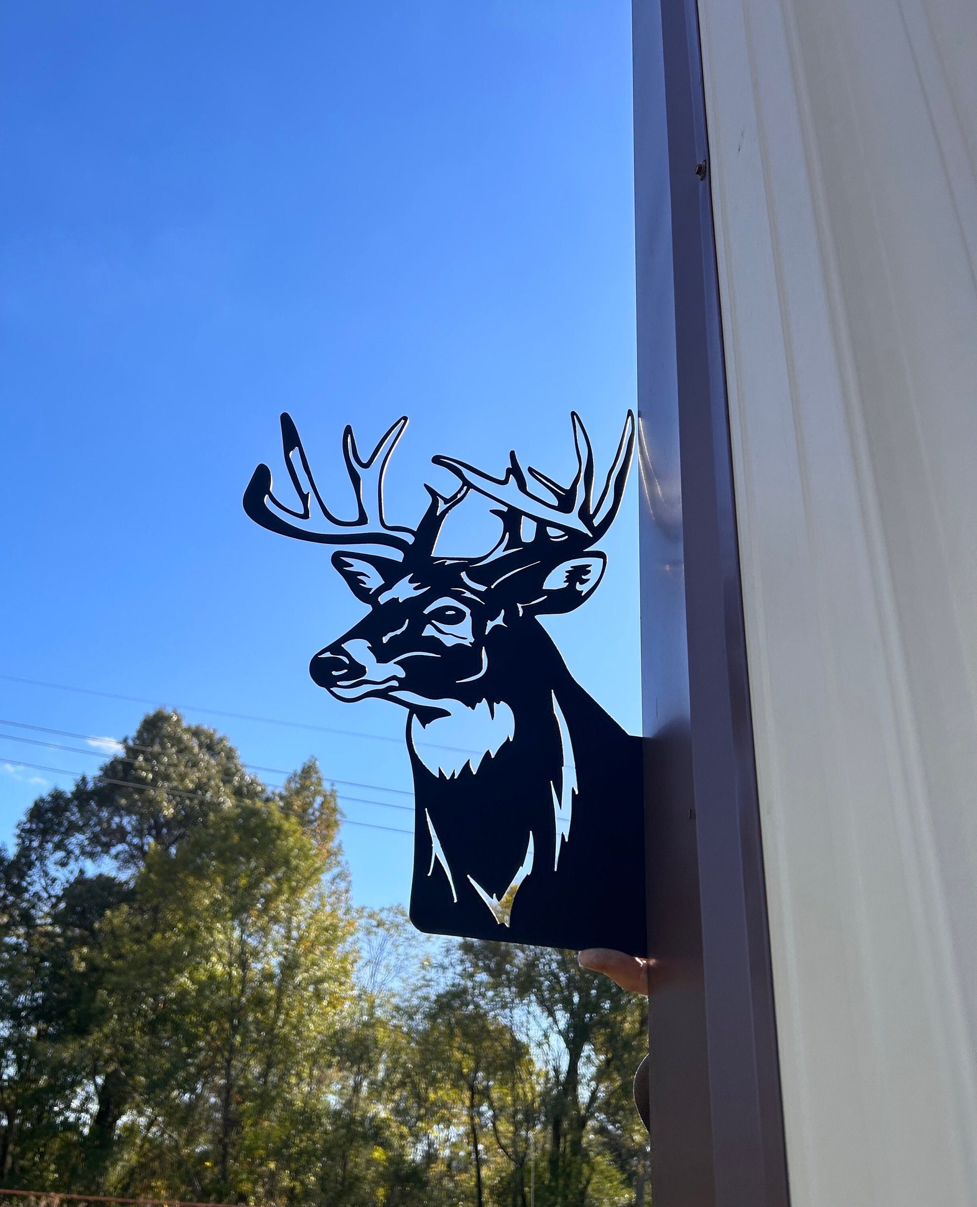 Metal yard art that is a peeping deer sign.